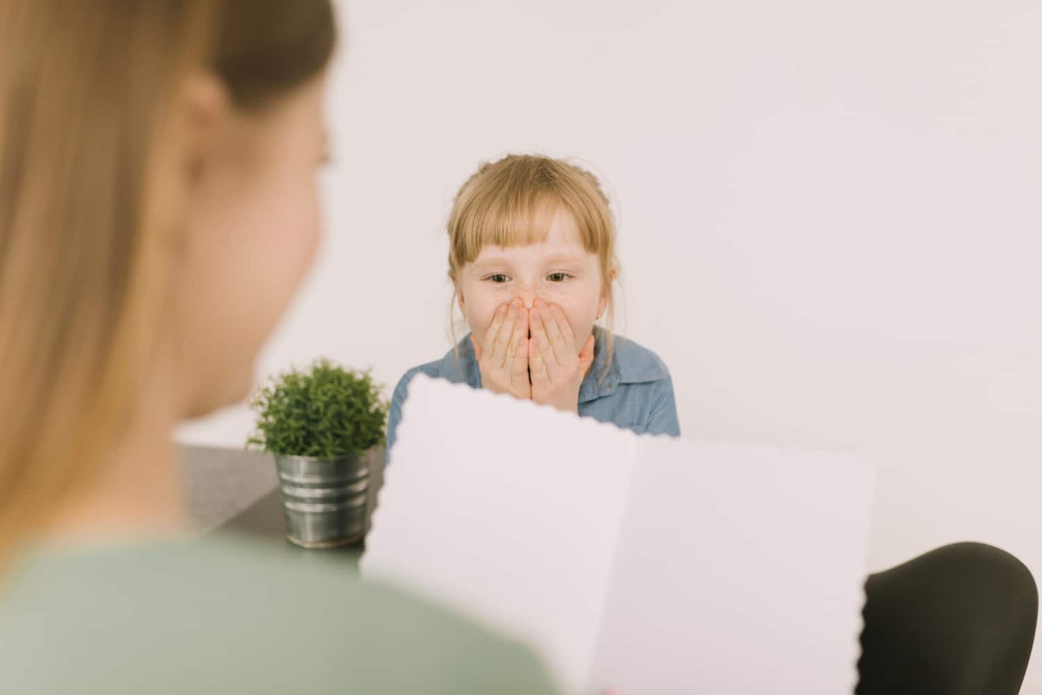 Young child covering her mouth during a conversation about a speech delay