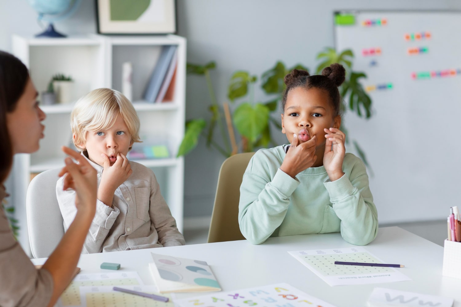 Speech-language pathologist practicing mouth sounds with two children